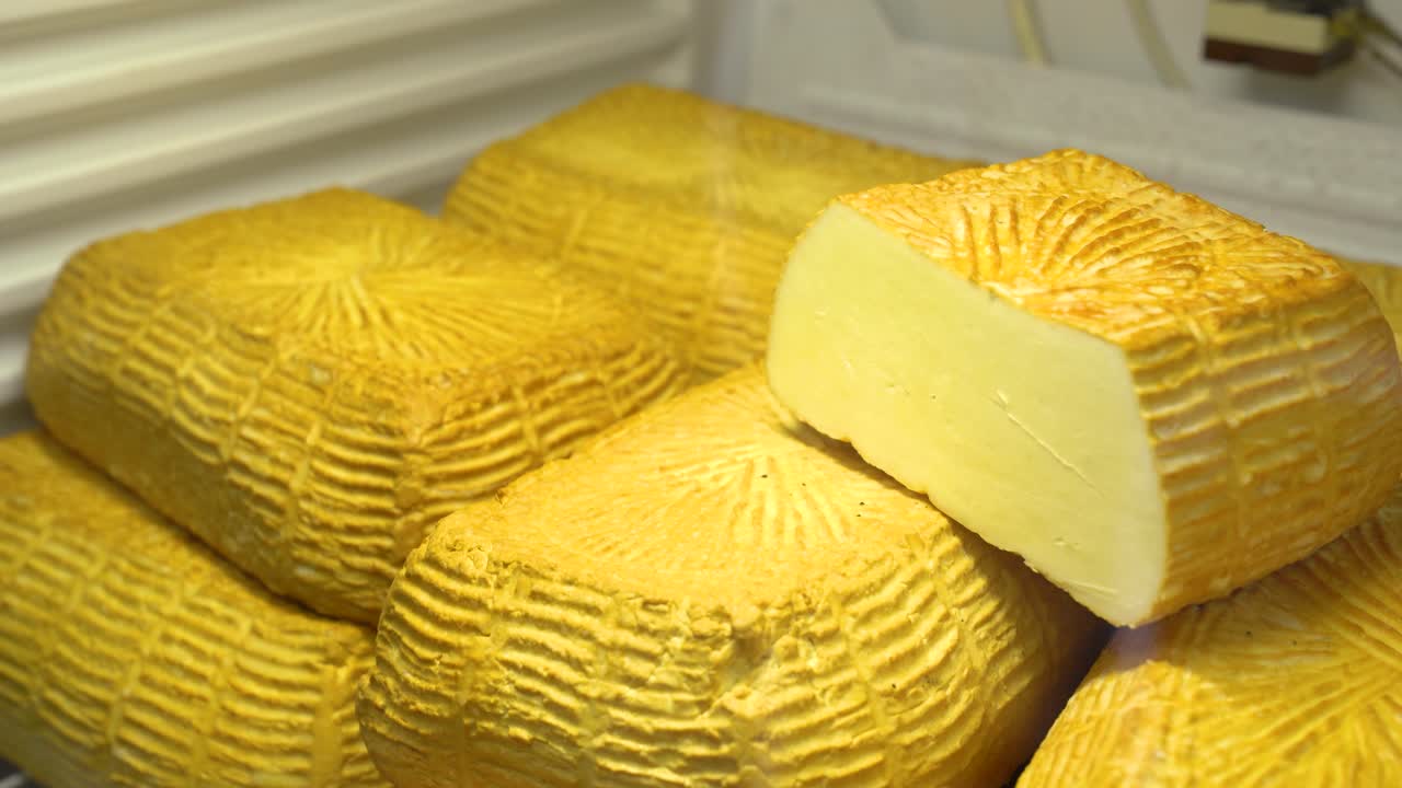 Close-up of Traditional Yellow Cheese Blocks with a Cut Slice