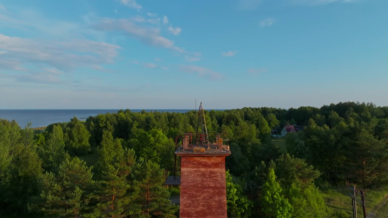 Flying over an old lighthouse near the coast, drone shot of moving towards and over, colorful summer golden hour