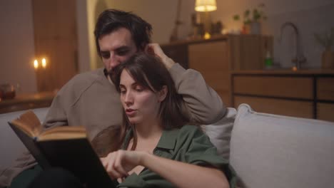 couple reading a book on the sofa at home