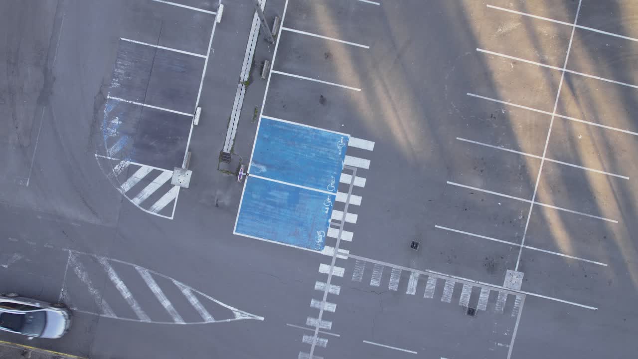 Bleka linjer på en tom asfaltsbelagd parkeringsplats, roterande flygfoto uppifrån