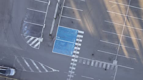 washed out lines of empty asphalt parking lot, aerial top down spinning shot