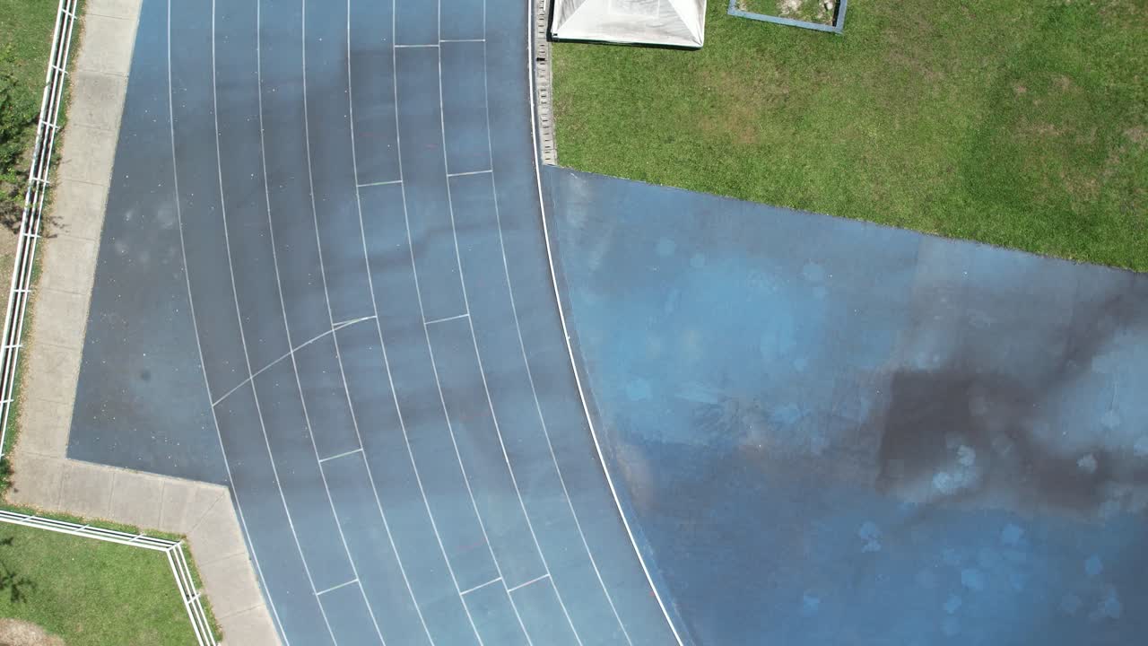 Drone footage showing a bird’s-eye view flight over the eight-lane running track at the Sports Park in Ibagué, Colombia. The long jump track is visible beside the main athletics track.