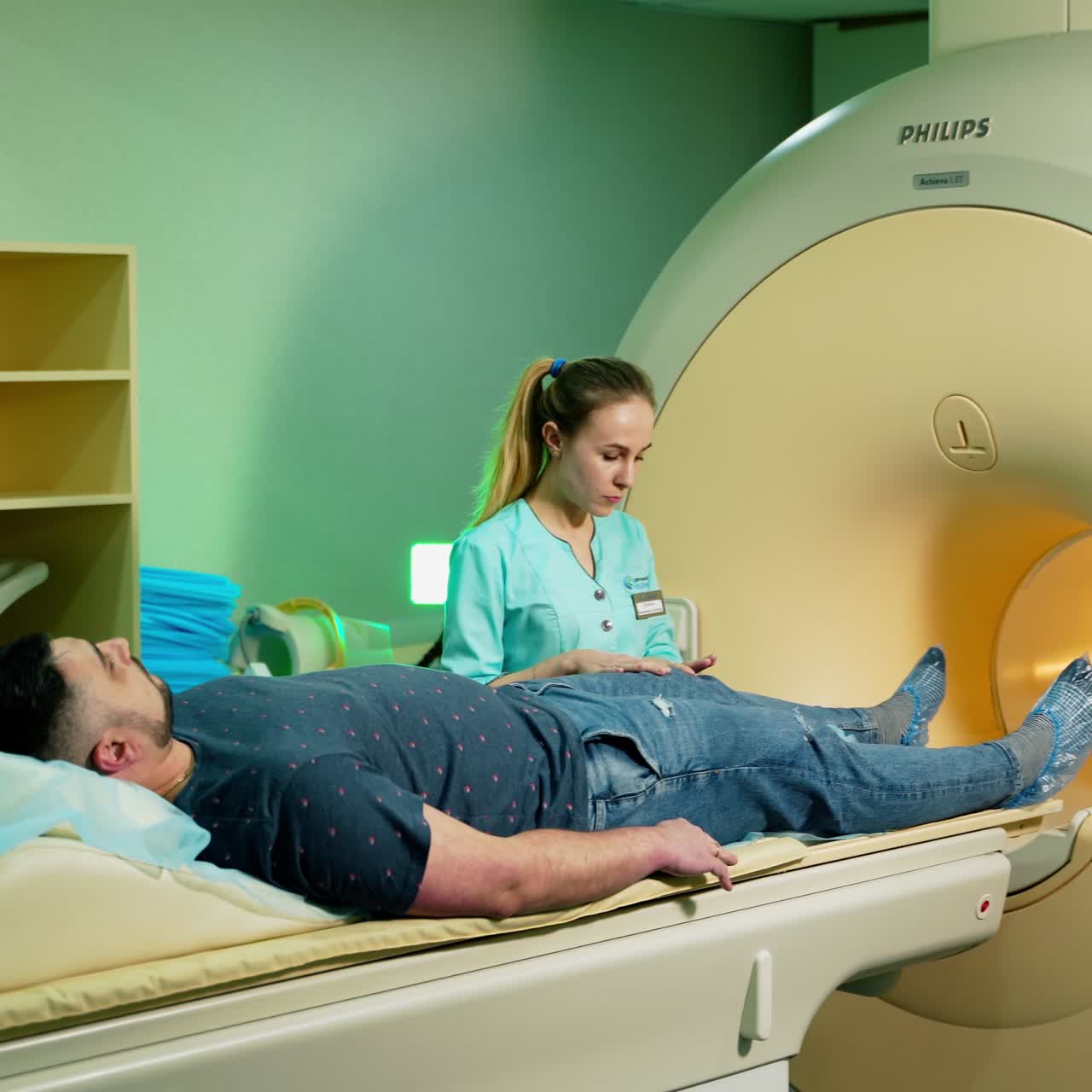 Male patient and a doctor before the mri procedure. Medical worker standing near the patient on the modern magnetic resonance imaging machine background.