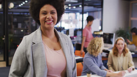 portrait of happy biracial businesswoman looking at camera at office