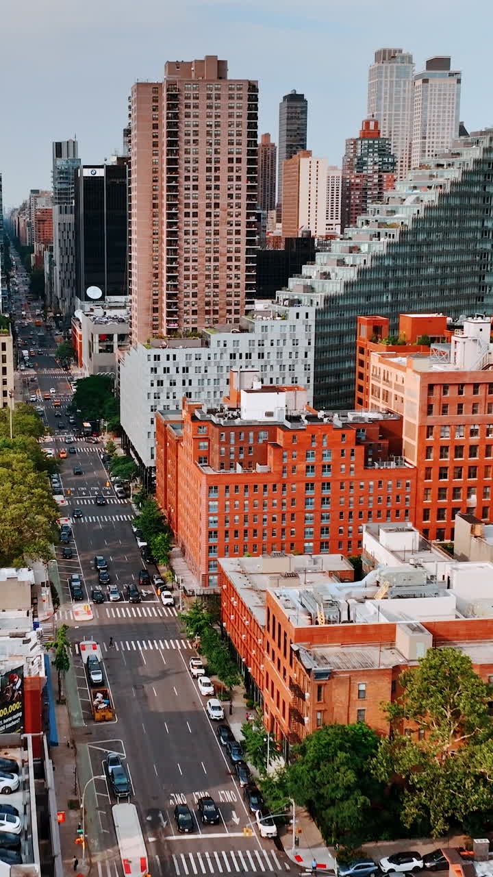 Flying above the busy multi-lane highway with heavy traffic. Drone footage along the beautiful New York buildings on sunny day. Vertical video