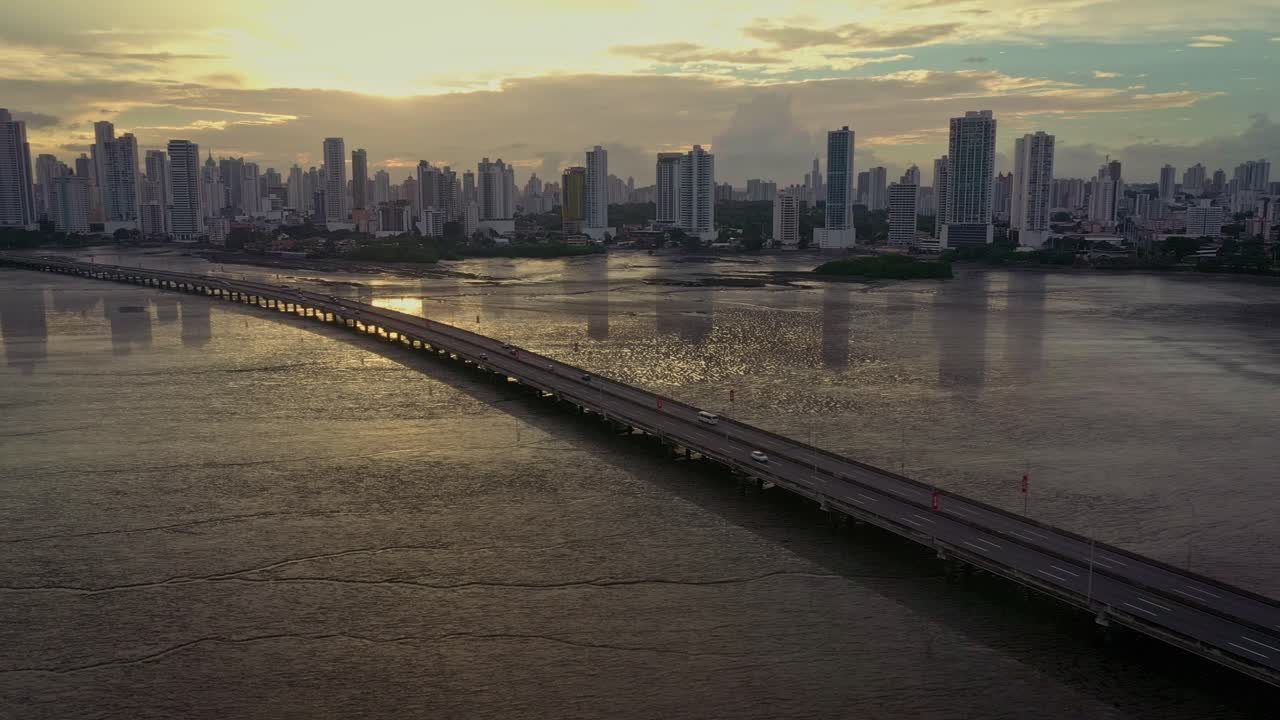 Sunset Cityscape with Bridge and Ocean Reflection