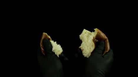 en manos con guantes sosteniendo un pan roto