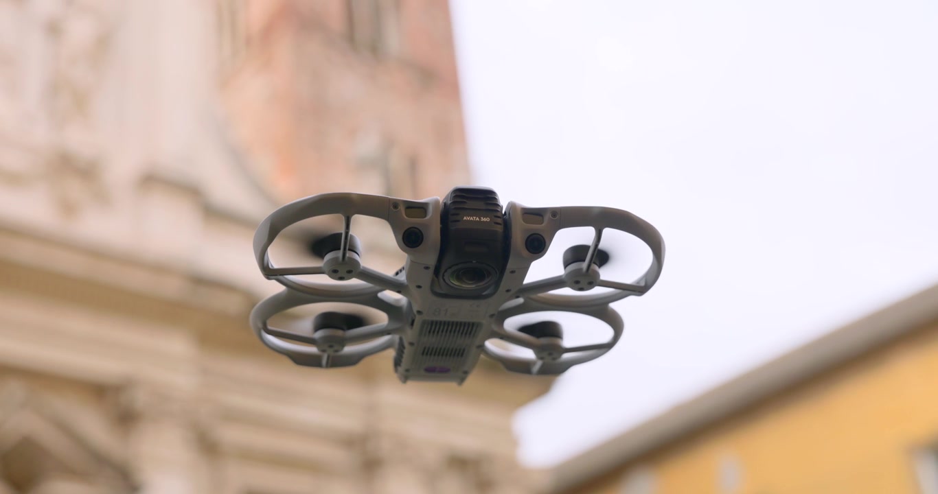 Piccolo drone con telecamera si libra stabilmente davanti a un'architettura antica e ornata, utile per temi di tecnologia, turismo o vlogging.