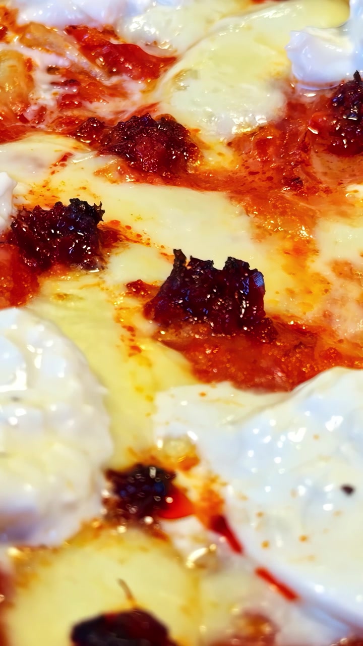 Una vista ravvicinata di una pizza con formaggio fuso e salsa piccante. Perfetto per la pubblicità alimentare o contenuti culinari.