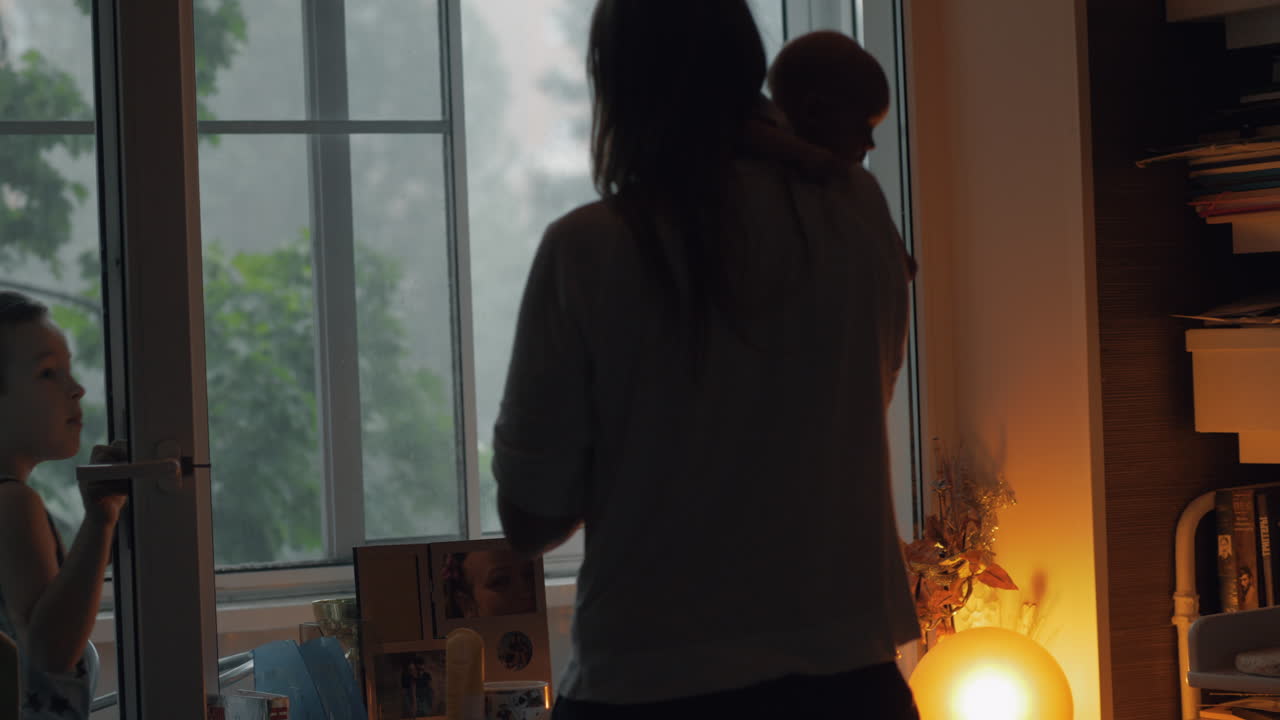 엄마와 아이들이 창밖을 바라보며 바에 많은 비가 내리고 있습니다.