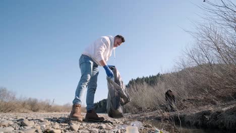 teamwork cleaning plastic on the beach. volunteers collect trash in a trash bag. plastic pollution and environmental problem concept. voluntary cleaning of nature from plastic. greening the planet