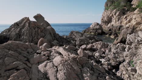 Nahaufnahme-Von-Felsen-Und-Steinen-An-Der-Zerklüfteten-Küste-Mit-Meer-Im-Hintergrund