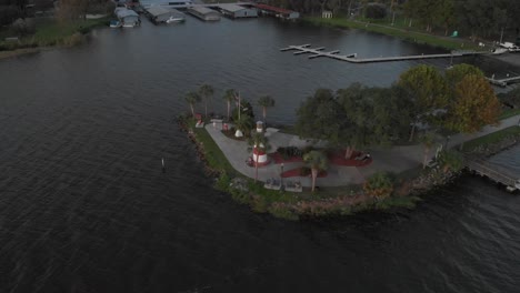Aerial-drone-wide-shot-of-marina-boat-dock-with-lighthouse-at-the-bay-palm-trees