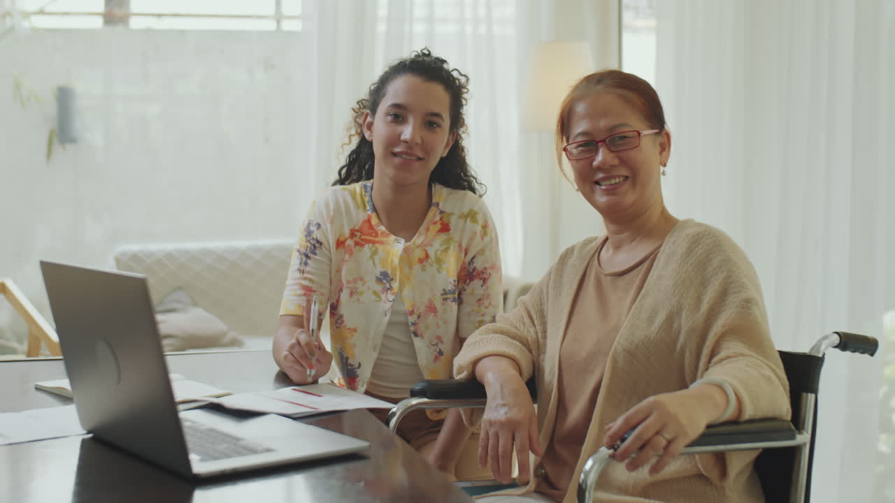 Caregiver assisting elderly woman in wheelchair at home