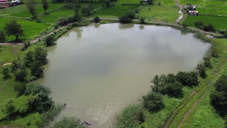 Vista-Aérea-Panorámica-De-Campos-Verdes-Y-Tierras-De-Cultivo-En-La-Zona-Rural-De-Maharashtra-Cerca-Del-Estanque-Durante-El-Monzón,-India