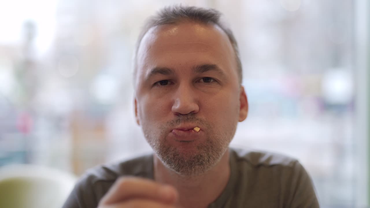 Young man portrait eating french fries in fast food restaurant. Harmful nutrition