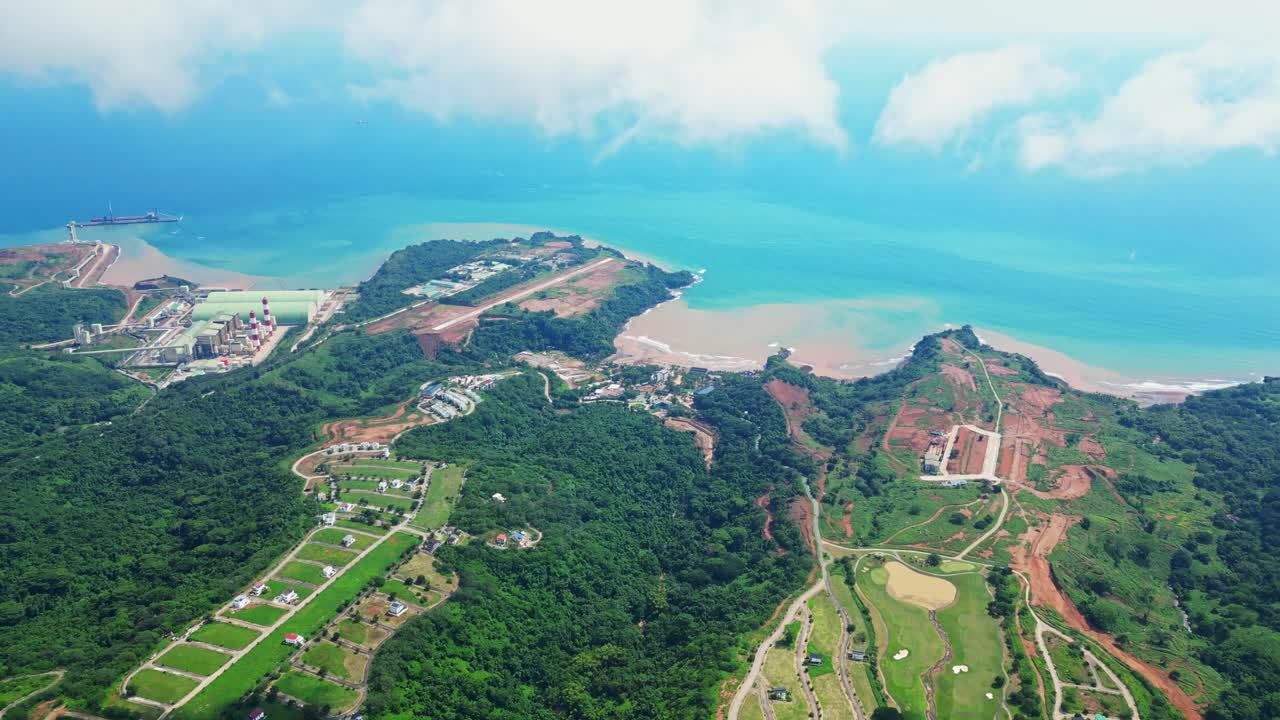 Sky‑high aerial of Tandatangan Signature Golf Course in Mariveles, Bataan, showing wide green fairways, winding roads, and surrounding hills leading toward the coastline