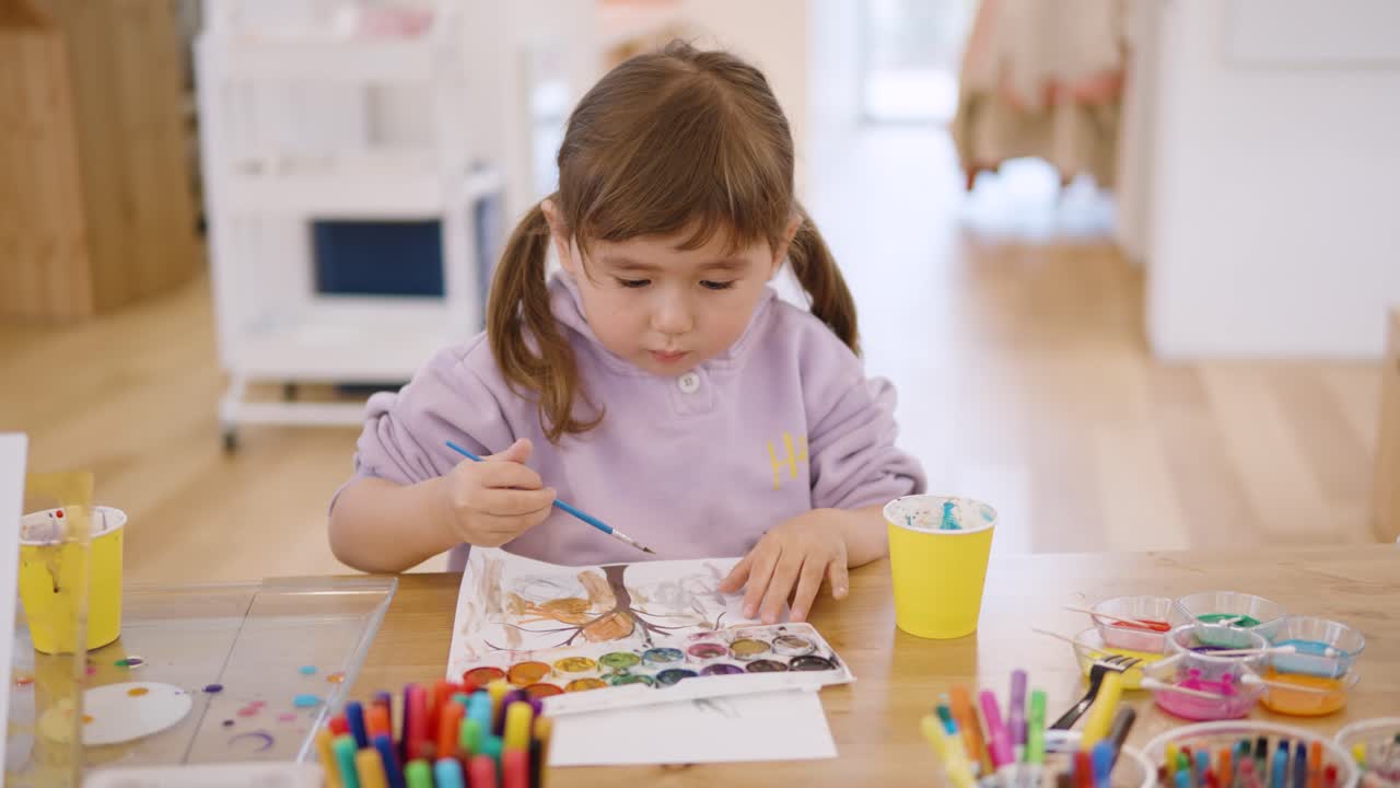 Toddler girl drawing and painting a beautiful tree with watercolors, creative and fun art activity, frontal medium static, slow motion