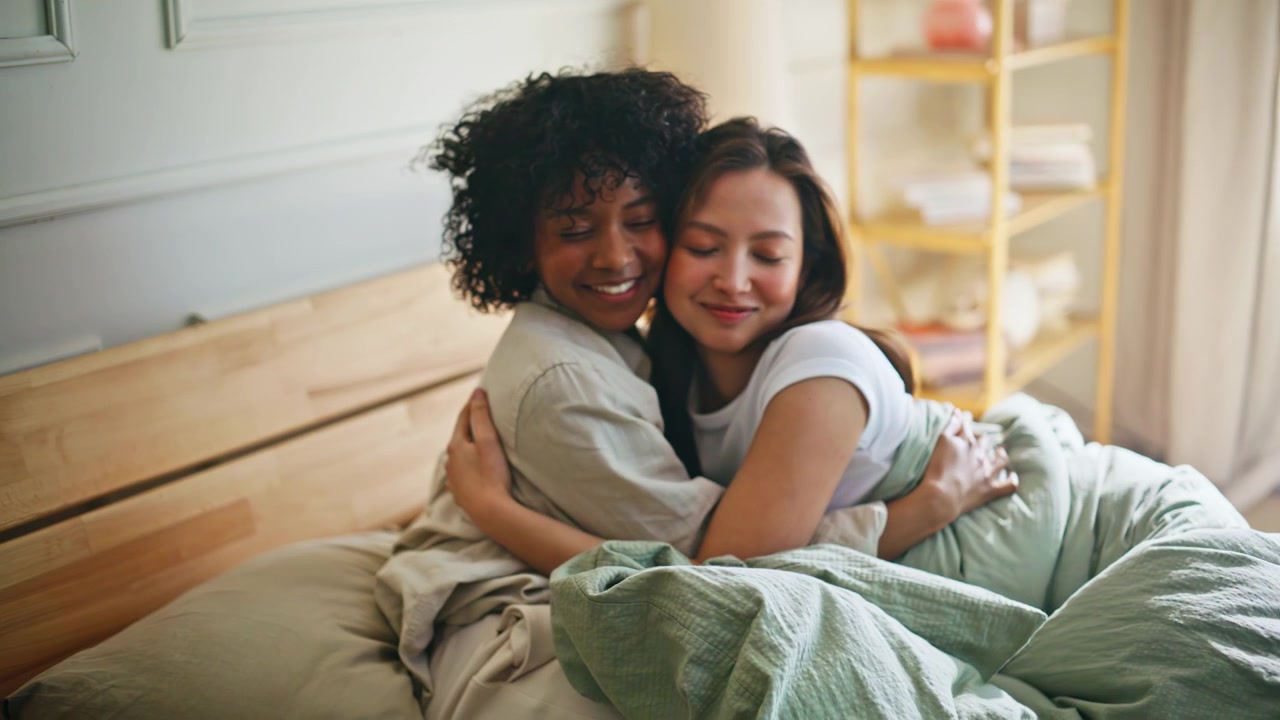 Coppia di donne che si abbracciano a letto al mattino. Stessa coppia che si coccola in camera da letto, amore tenero