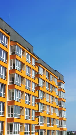 beautiful design of multistory building. new apartment with balconies against blue sky. exterior of residential building. camera rising up. slow motion vertical video