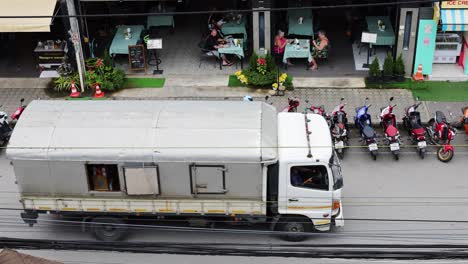 truck passing by parked motorbikes and tourists