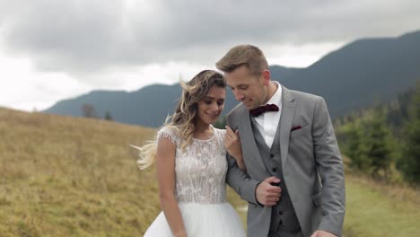 Lovely-young-newlyweds-bride-groom-walking-on-mountain-slope,-holding-hands,-wedding-couple-family