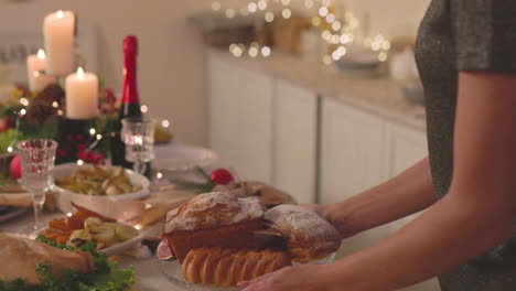 mujer irreconocible poniendo deliciosos pasteles en la mesa de la cena de navidad