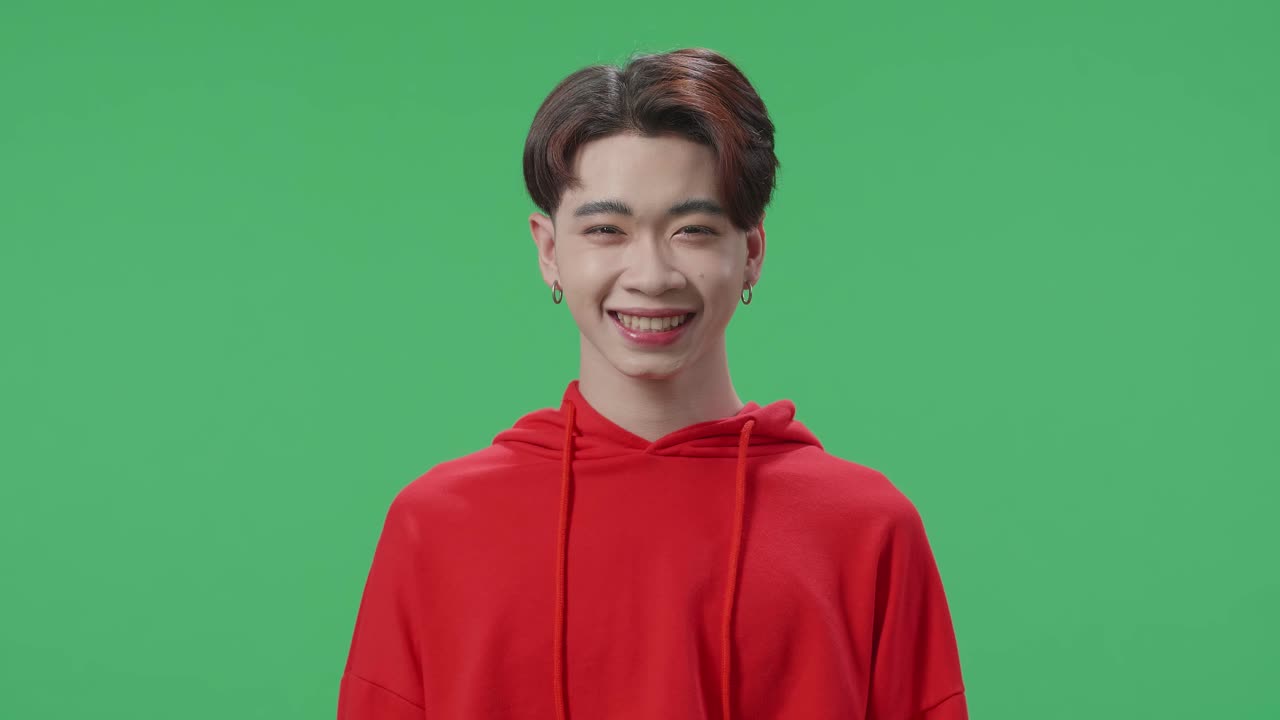Smiling Asian Transgender Male Looking At Camera In The Green Screen Studio