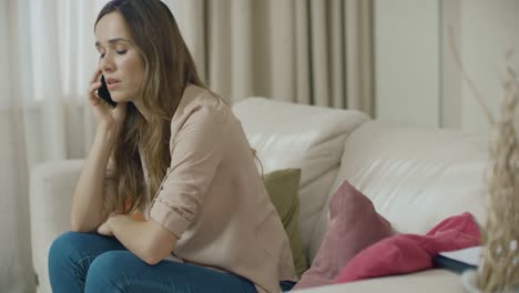 Sad-woman-talking-phone-on-home-sofa.-Depressed-customer-using-mobile-phone