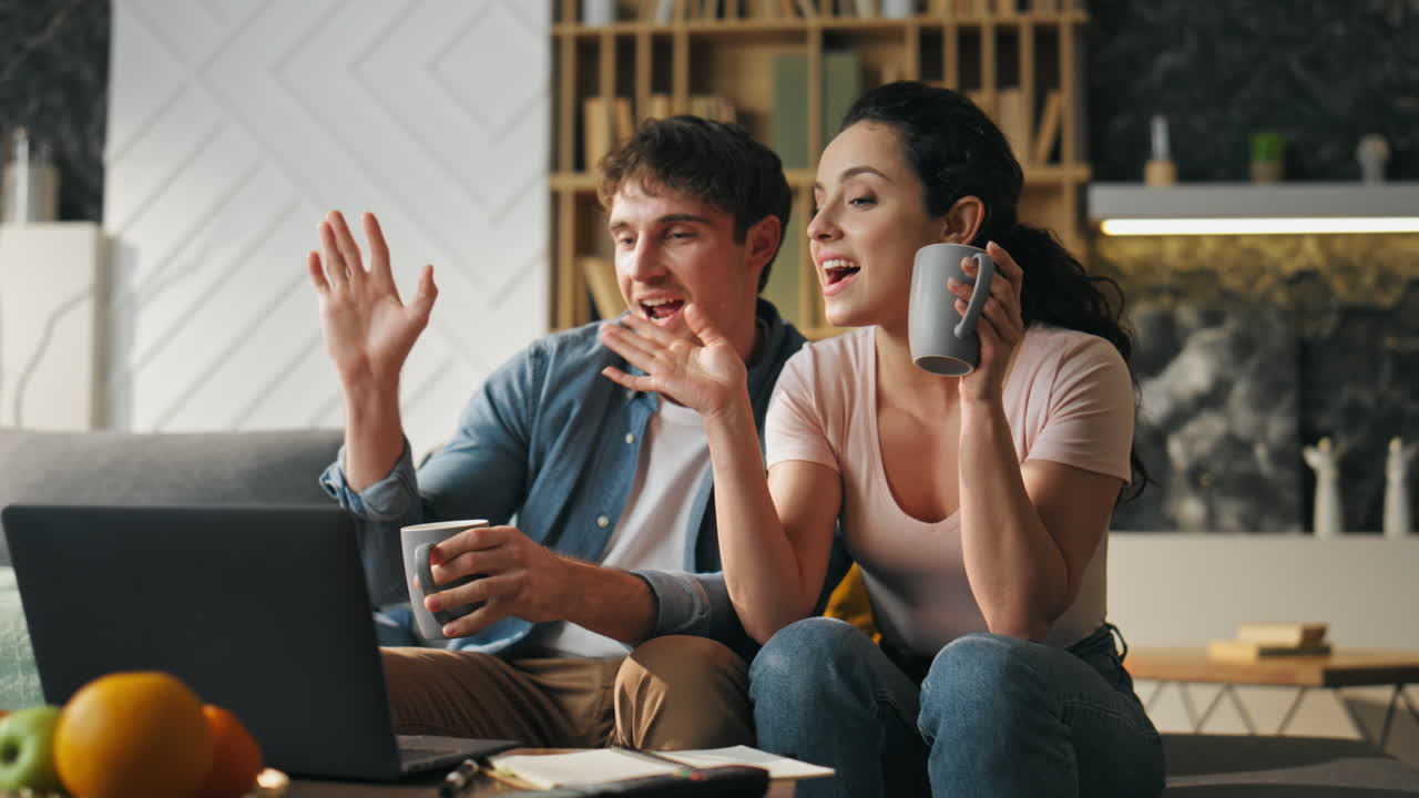pareja termina la llamada de video agitando las manos a la cámara del portátil de cerca. reunión en línea