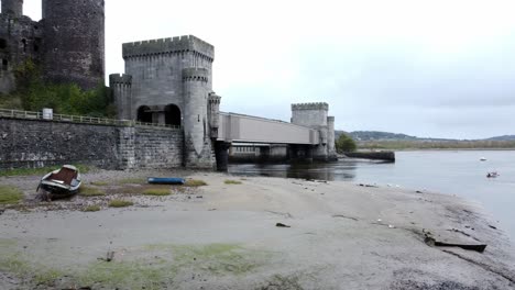 conwy castle marea baja barcos amarrados en banco de barro vista aérea subiendo órbita derecha