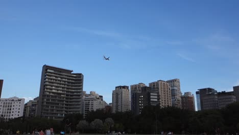 avión volando sobre edificios modernos en la ciudad, parque rodeado de rascacielos