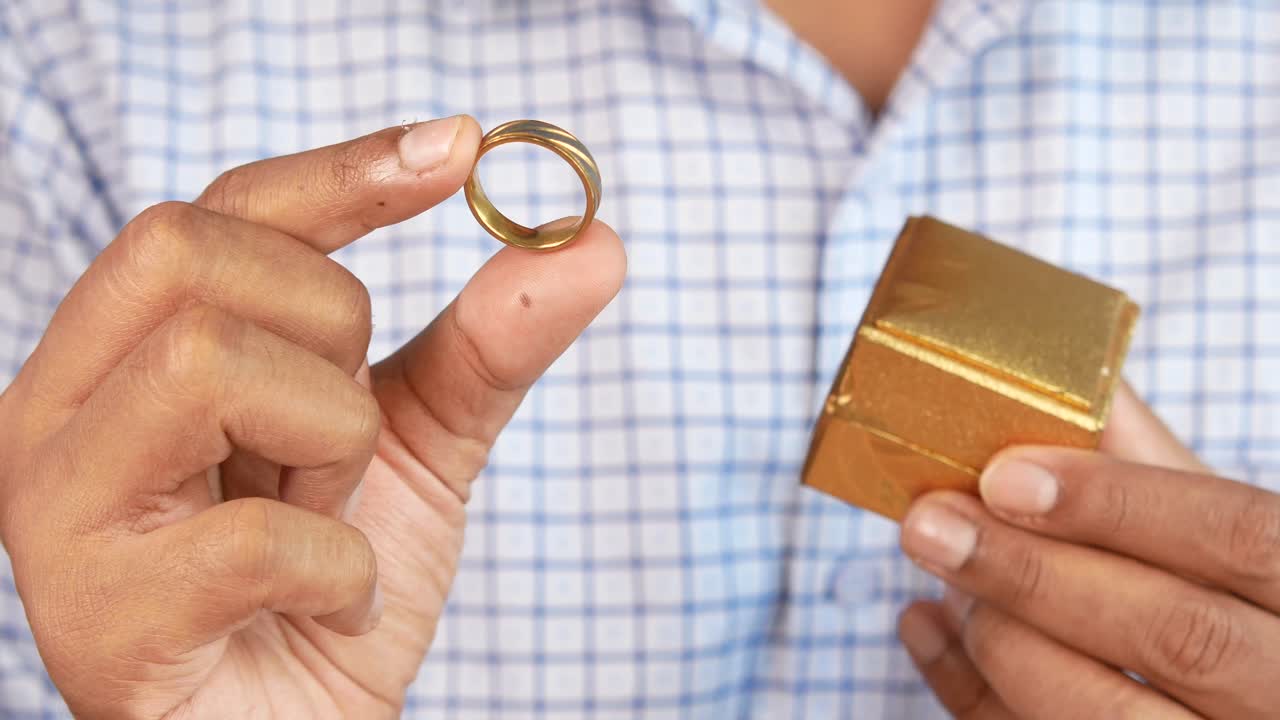 금 반지 와 선물 상자 를 들고 있는 남자