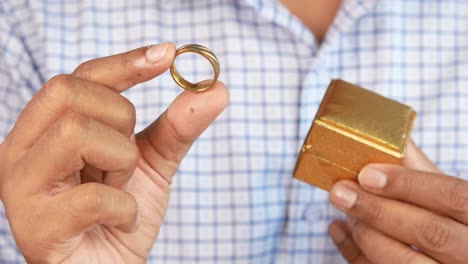 hombre con un anillo de oro y una caja de regalos