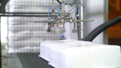 manipulador robótico que mueve un contenedor de plástico a la cinta transportadora en la fábrica