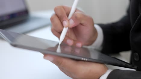 businessman using stylus pen signing contract on digital tablet at work in office indoors. close up hand write business agreement of contract. electronic signature on tablet computer.