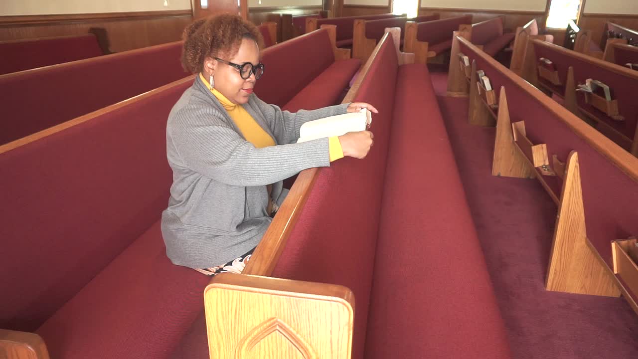 화창한 날 빈 교회에서 행복하게 신의 말씀을 읽는 안경을 쓴 흑인 여성