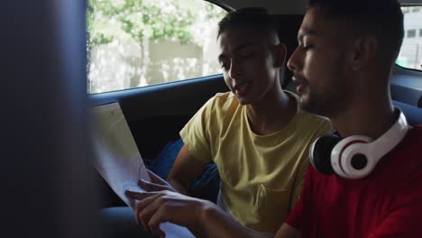 two mixed race friends using map and talking in cab