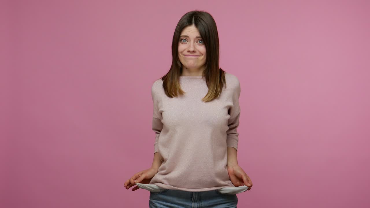 불하고 걱정스러운 갈색 학생 소녀는 화가 나고 빈 주머니를 밖으로 내보내며 돈이 없다고 제스처합니다.