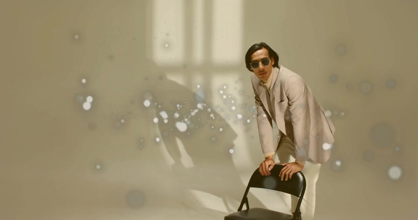 Model lifting sunglasses, stepping on chair, leaning, walking then sitting amid sparkles in fashion