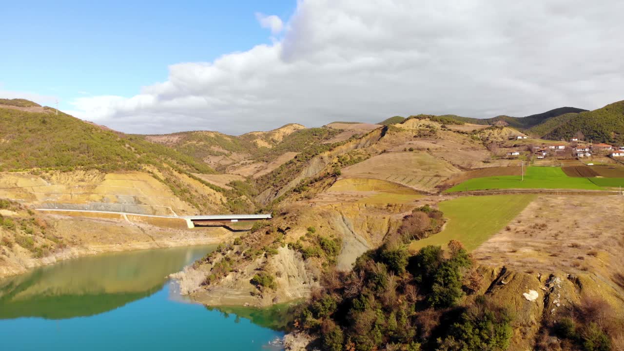 colores vivos del paisaje rural cerca de la costa del lago de montaña y puente sobre aguas tranquilas y claras que reflejan las nubes