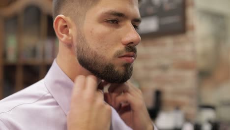el novio ajusta la camisa en el fondo de la barbería. preparándose para ir a la novia