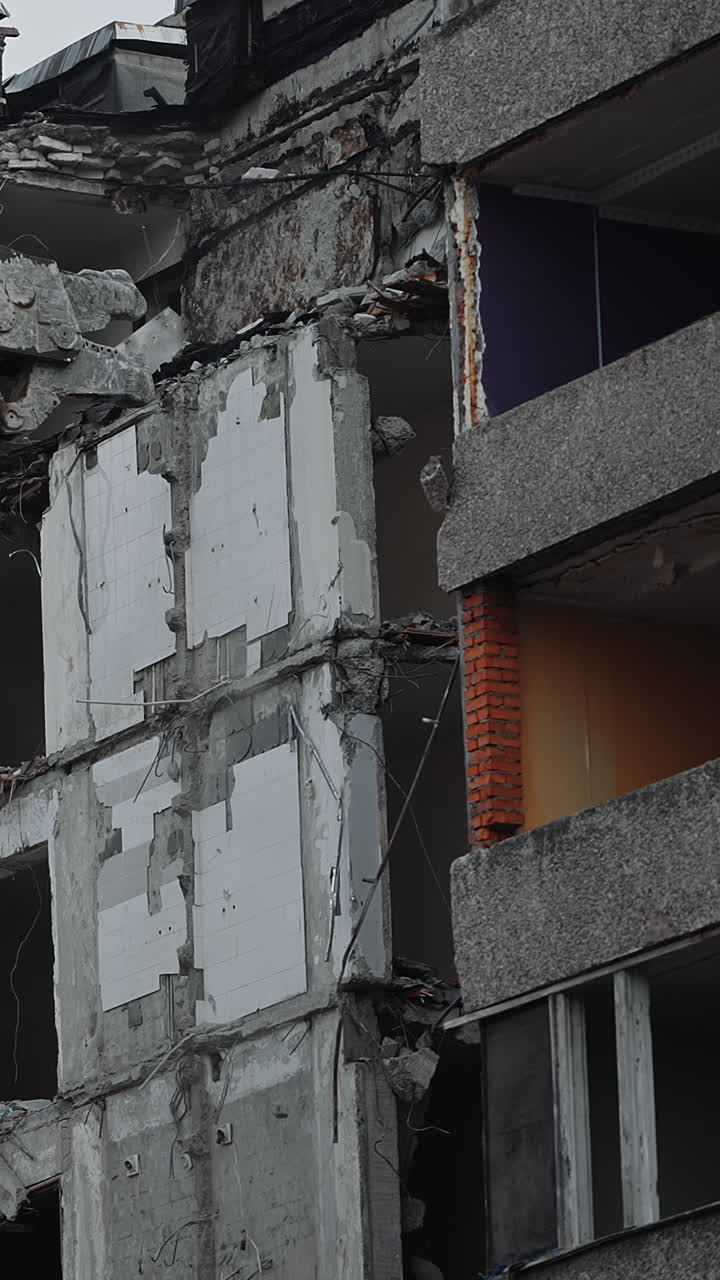Big hydraulic claw grasps the concrete floor of the destroyed house. Excavator crasher reaches high to break the walls and floors of the ruined building. Vertical video