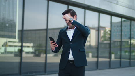 Closeup-man-receiving-good-news-at-street.-Business-man-using-phone-outdoor