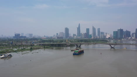 aerial slow push in on freighter transporting shipping containers on the saigon river on a sunny clear day