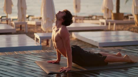 Bare-chested-guy-took-a-special-strip-for-yoga-and-meditation-on-Sunny-Beach-in-the-morning.-Exercising-in-the-morning-on-a-private-beach