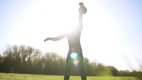 athletic male lifting up the poise in black coloured sports wear.outdoors. green grass. footage from below