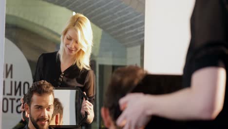 female hairdresser showing man his haircut in mirror