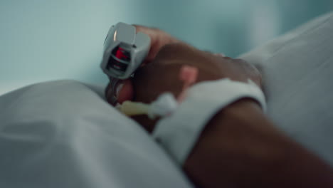 patient finger pulse monitoring device closeup. medical catheter on male hand.