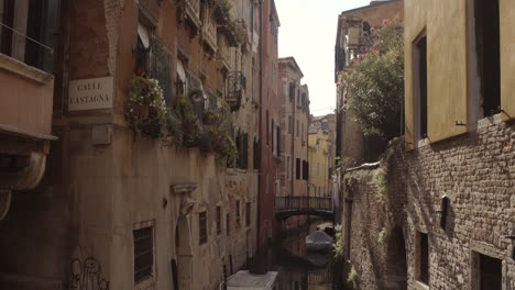 wide tilt up shot of historic water canal street cale castagna with brick wall, venice, italy